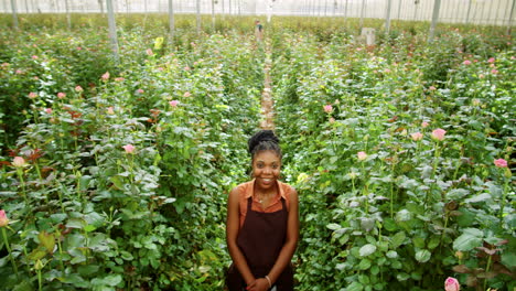 african american woman posing for camera with smile in flower greenhouse