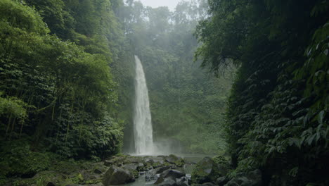 water falling down over the hidden nung nung waterfall in indonesia