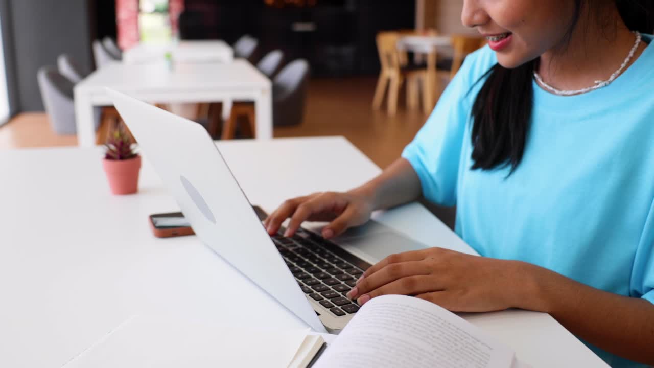 Asian young teenage woman use and typing on laptop computer at library of school. University Library education and Student Learning concept.