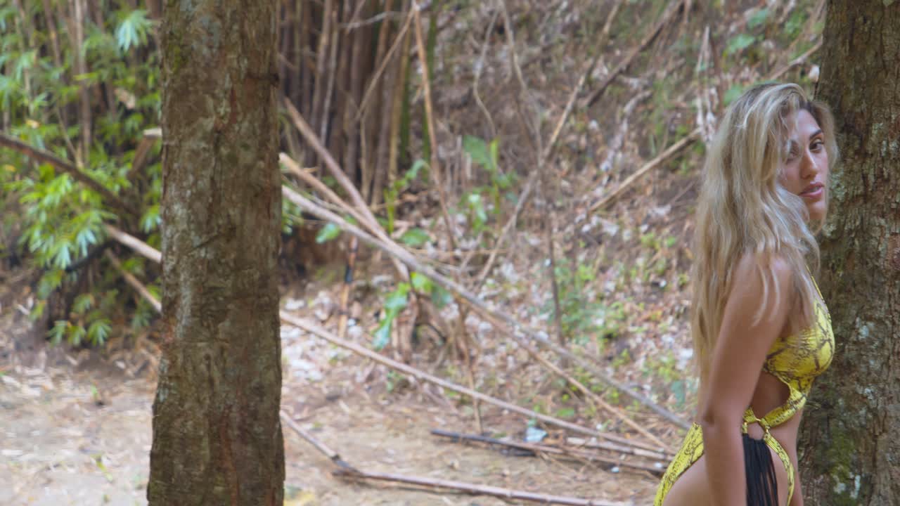 chica de cabello rubio camina a lo largo de la orilla del río en un sexy bikini tanga amarillo