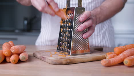 male hands grating carrots on cutting board