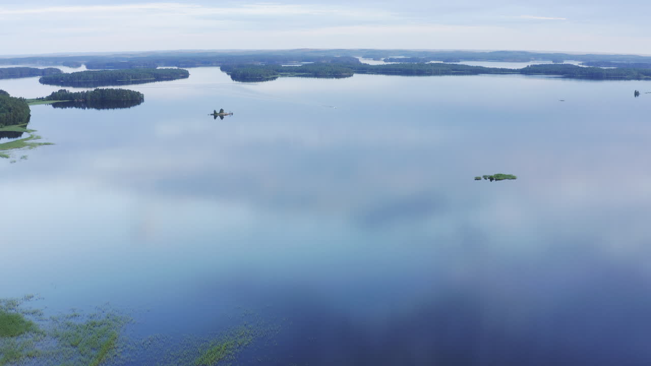 일몰 후 황금시간까지 잔잔한 푸른 호수 표면에서 먼 거리를 운전하는 작은 모터보트의 드론 영상