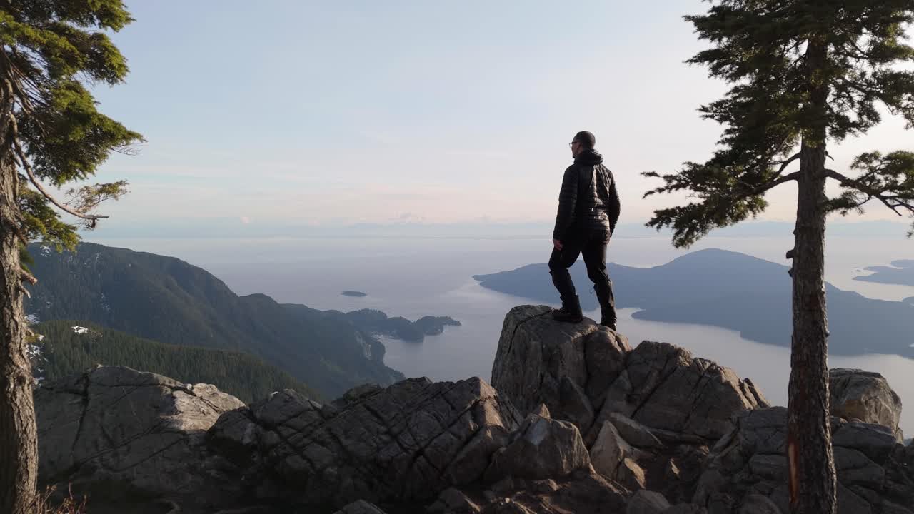 Hiker Celebrates on Mountain Top Overlooking Ocean and Islands in BC