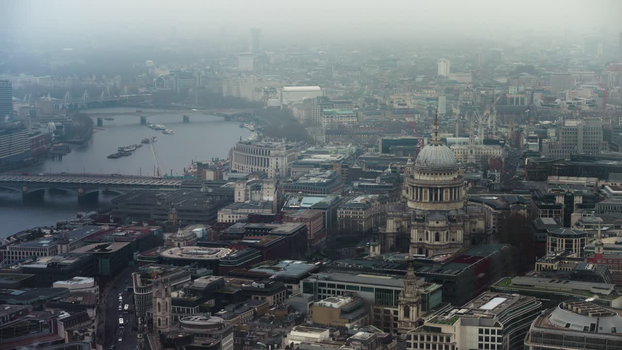 Aerial view showing a cityscape of London; with St pauls and the River Thames in fog.