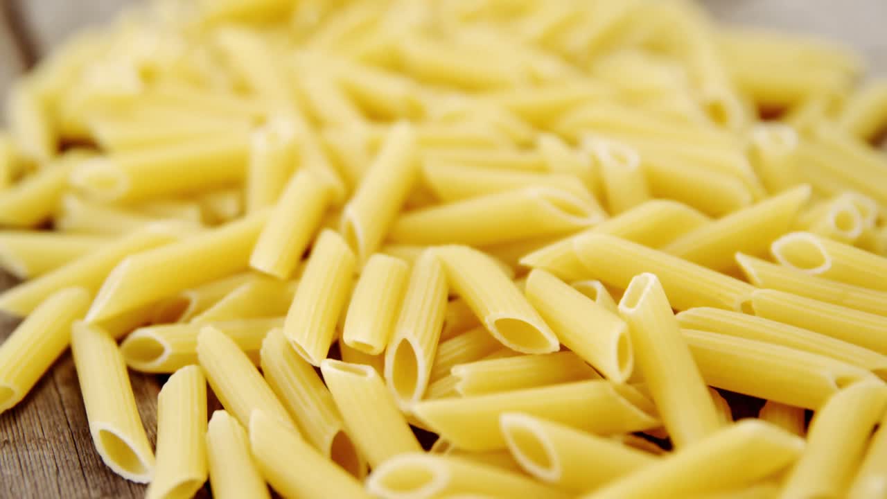 una pila de pasta de penne en un fondo de madera