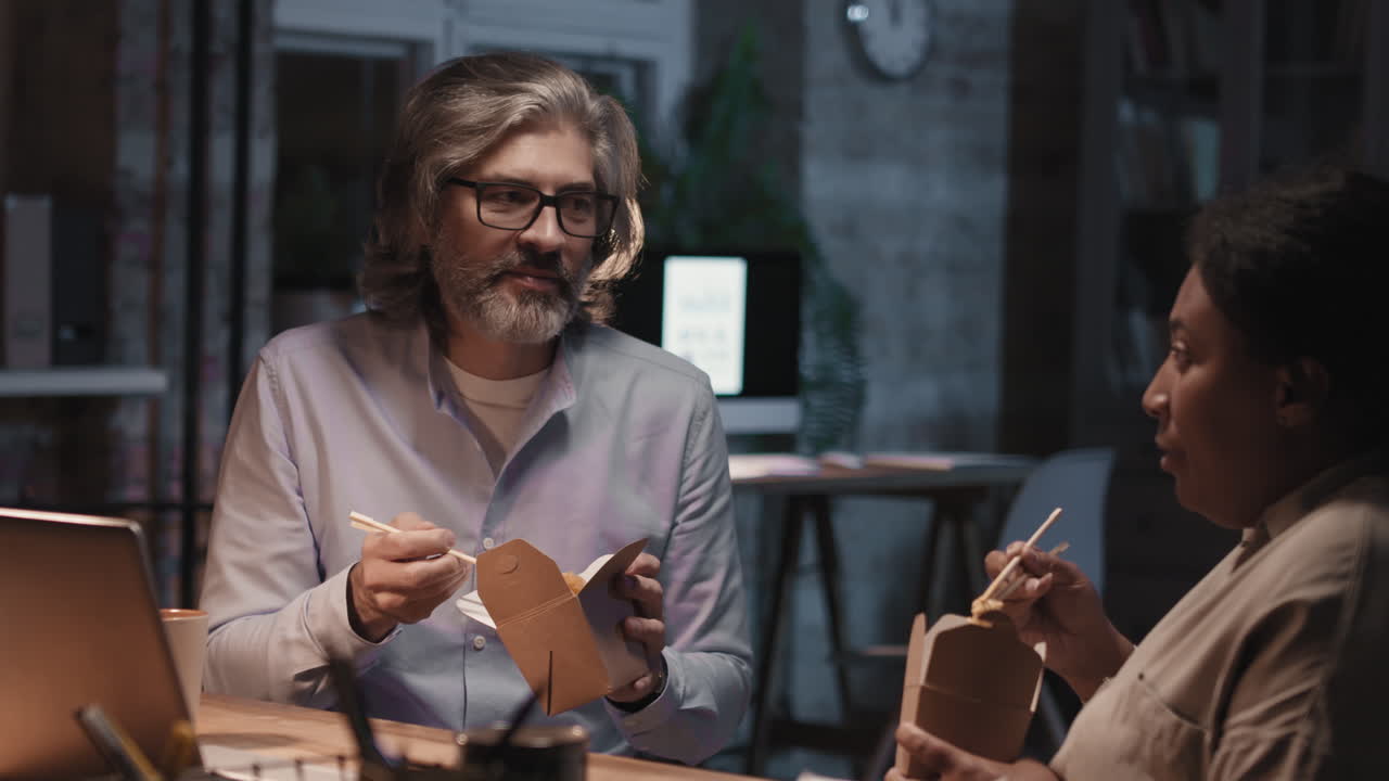 Colleagues Eating Late-Night Takeout Noodles in an Office