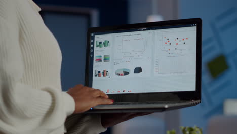 Close-up-of-dark-skin-woman-typing-on-laptop-standing-in-start-up-office