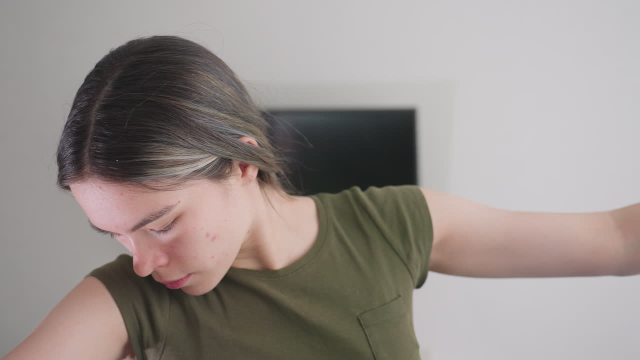 Close up of lady folding fluffy blue blanket indoors, hands arranging soft fabric with focused expression, natural daylight brightening modern interior with television visible in background