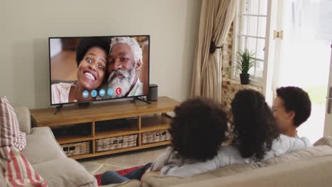 African-american-family-sitting-on-sofa-making-video-call-with-friends-on-tv-screen