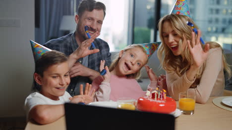 Family-celebrating-birthday-online.-Mom,-dad,-kids-waving-hands-laptop-screen