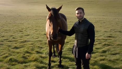 man petting a horse in a grassy field