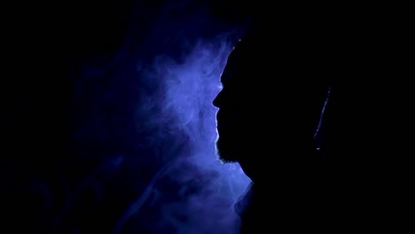 Silhouette-of-a-man-on-the-dark-background-with-blue-light-and-smoke-around
