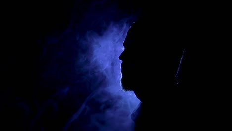 silhouette of a man on the dark background with blue light and smoke around