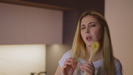 emotional woman performs singing into spoon in kitchen