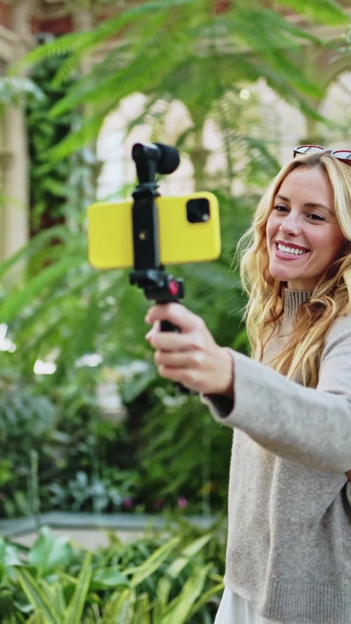 Donna sorridente che registra un video con lo smartphone in serra