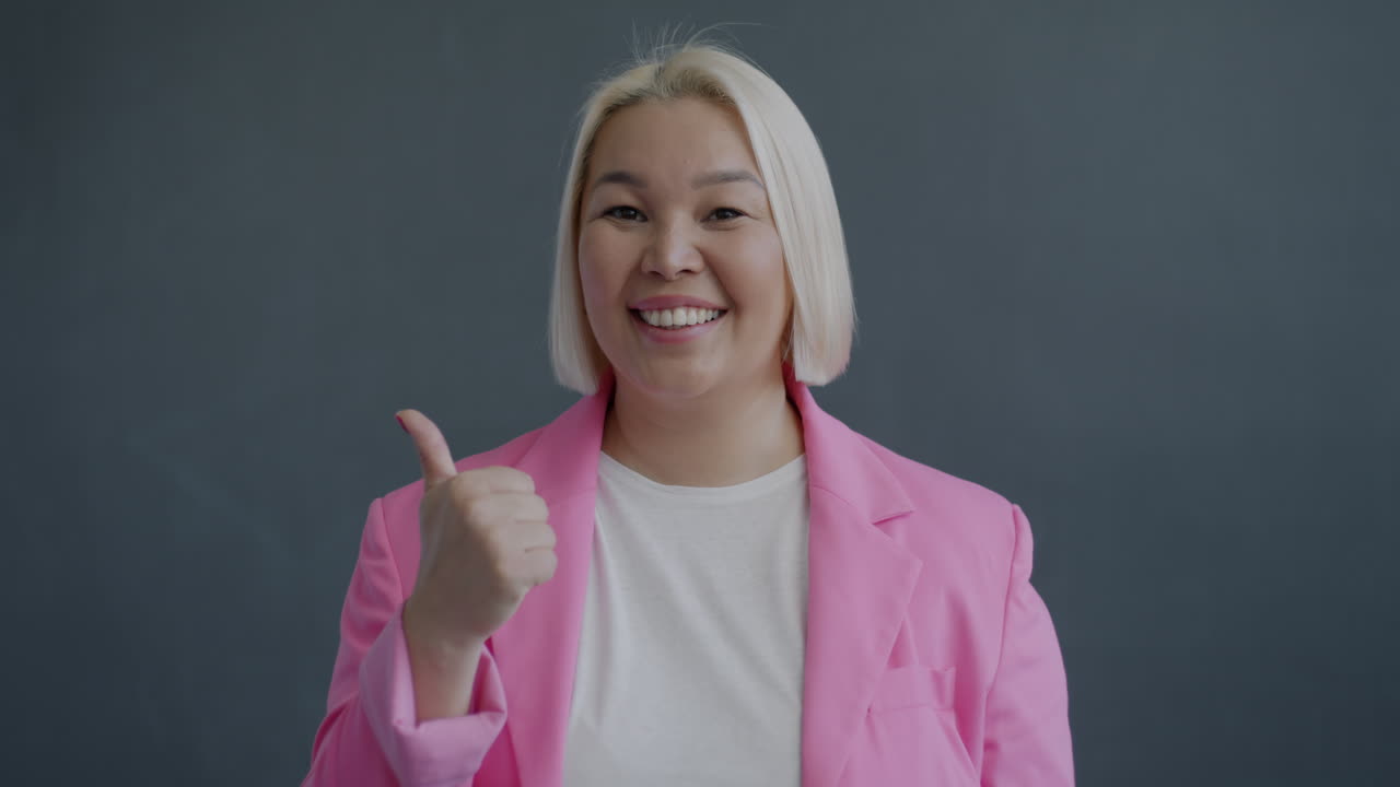 Smiling Woman in Pink Blazer Giving Thumbs Up