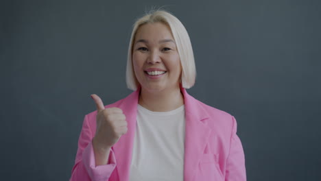 smiling woman in pink blazer giving thumbs up