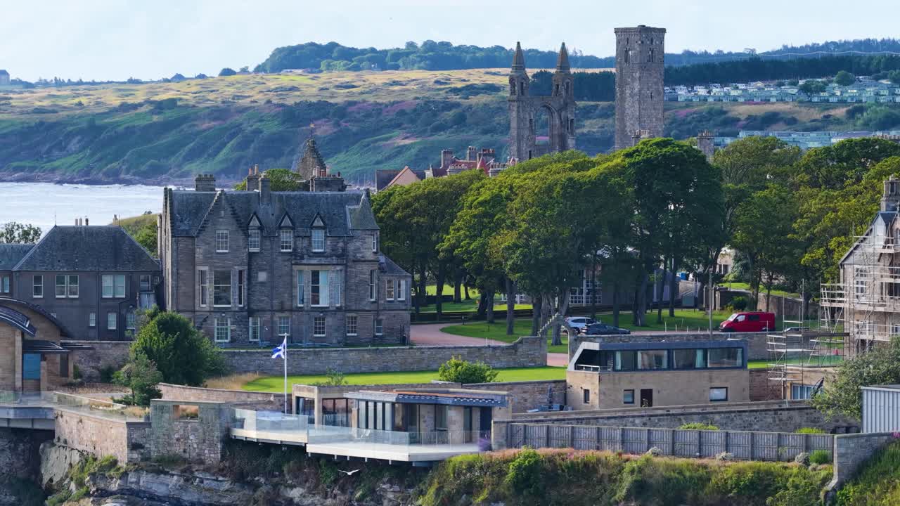 Daytime drone shot slowly panning across historic St Andrews castle, cathedral ruins, and coastline