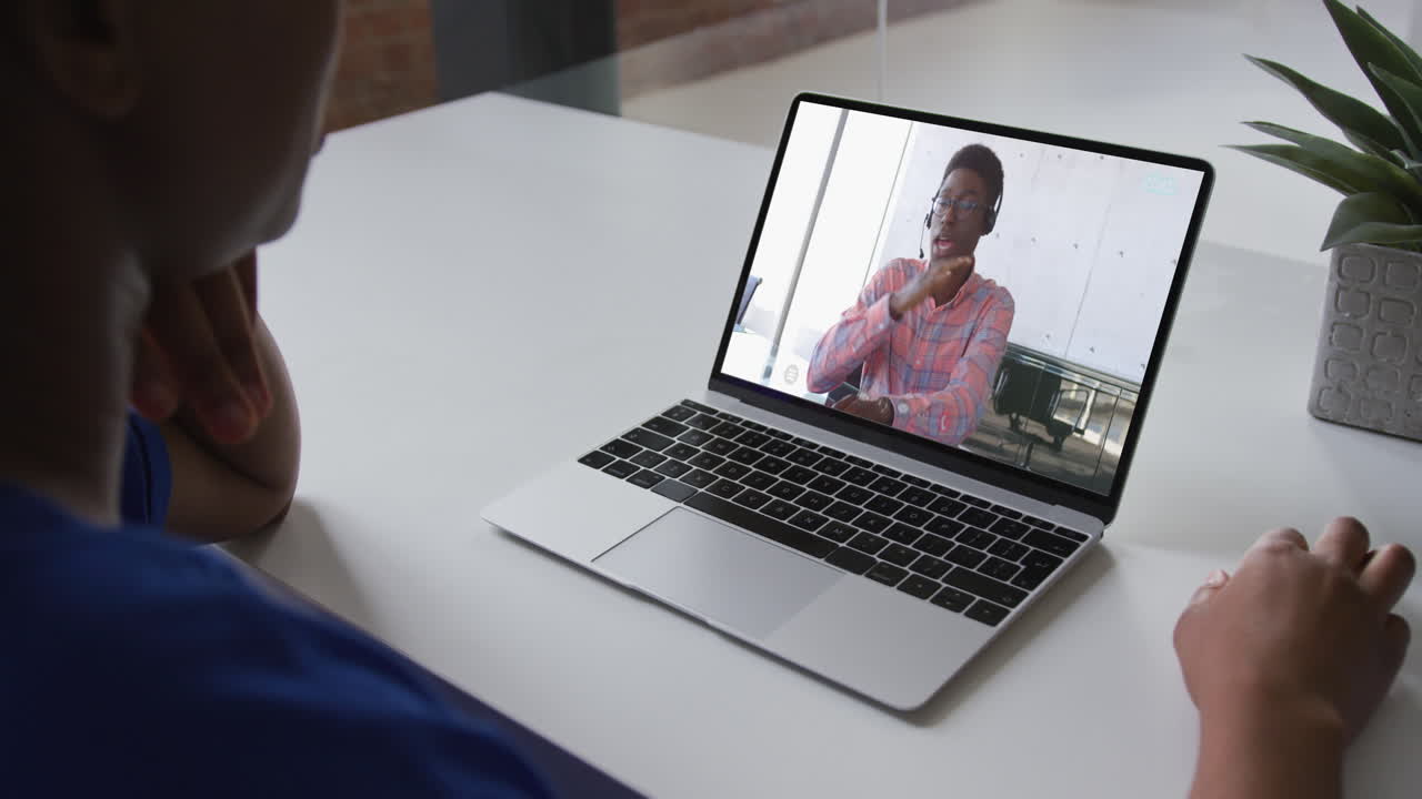 African american woman talking on video call on laptop with male office colleague at home