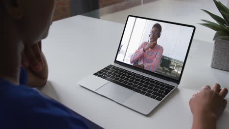 african american woman talking on video call on laptop with male office colleague at home