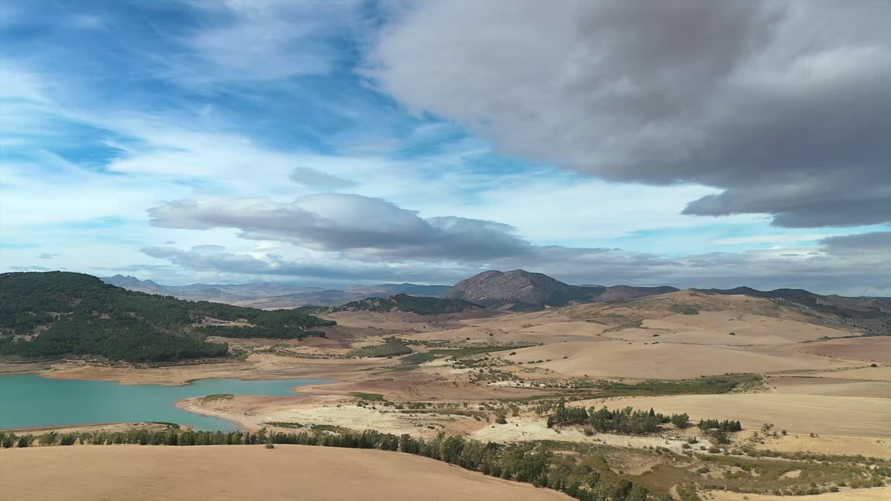 Aerial drone view of vast, arid landscape with a reservoir winding through it, Andalusia, Spain