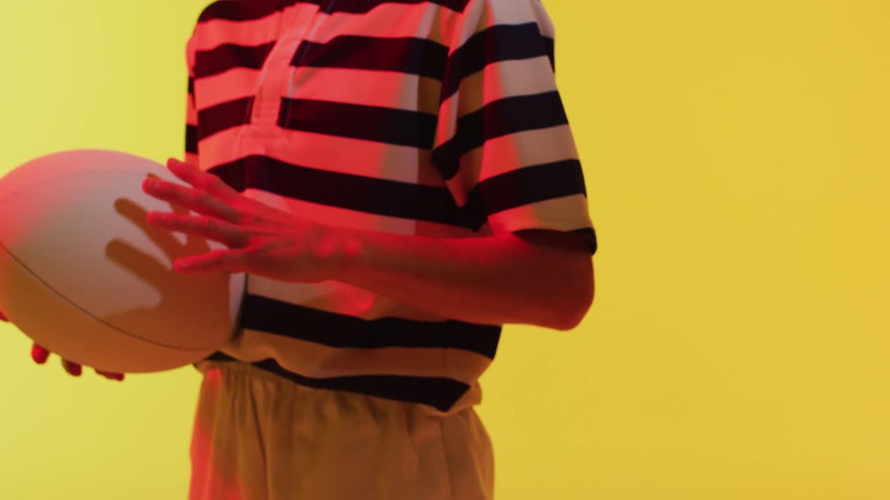 jugadora de rugby caucásica con pelota de rugby sobre iluminación amarilla de neón