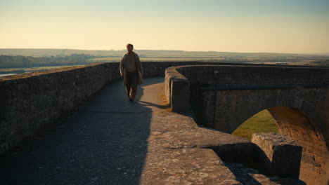 man walking on an ancient castle wall at sunrise