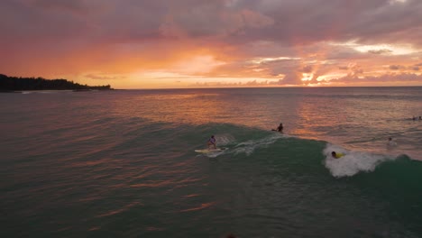 surfista atrapando olas con un hermoso fondo de puesta de sol de hawaii, vuelo aéreo de drones