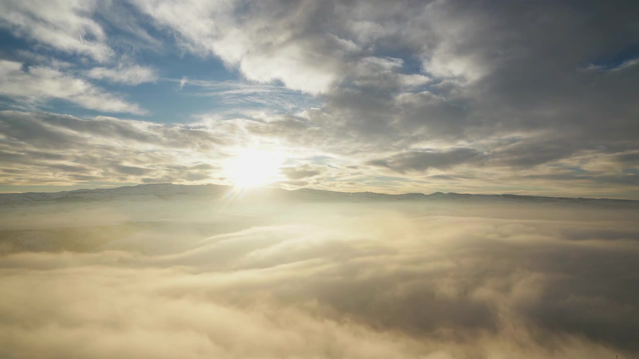 Vista aerea dell'alba sulle montagne innevate sopra le nuvole