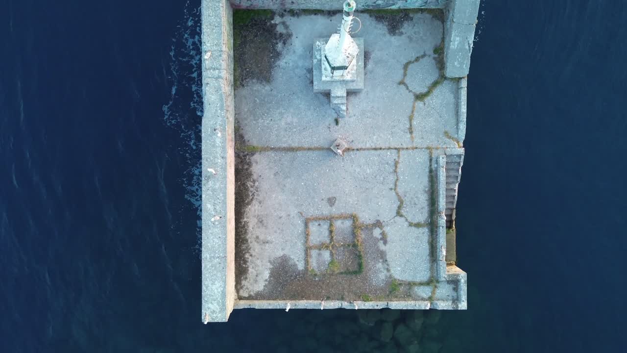 Aerial view of small iconic lighthouse at Kalamata port, top view, push in isolated footage 4K