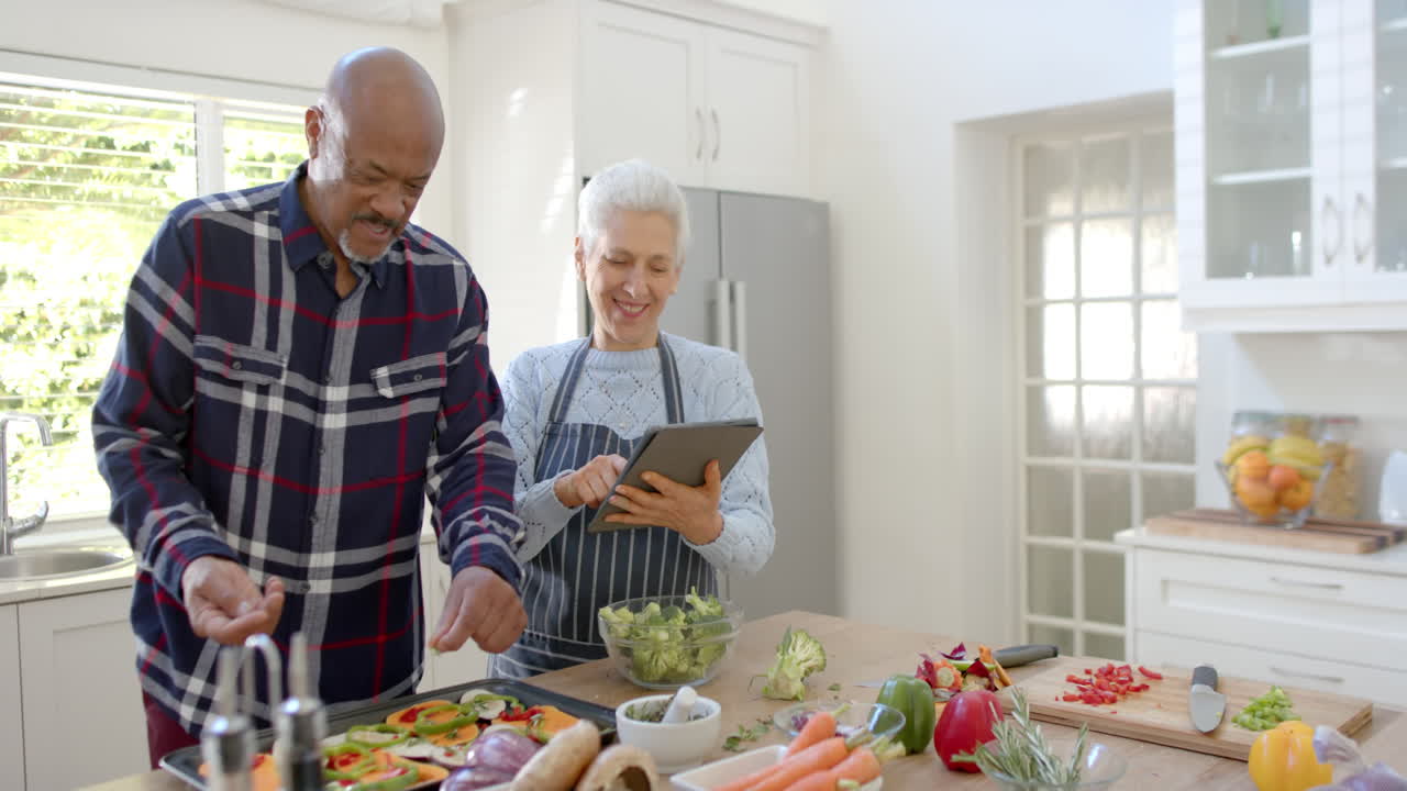 pareja de ancianos feliz preparando verduras, usando tableta en la cocina, espacio de copia, cámara lenta