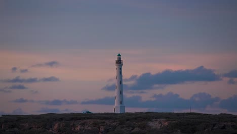 see a lighthouse time-lapse at sunset in aruba, beacon illuminating the caribbean coastal landscape