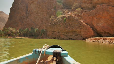 boat approaching rocky canyon under modern bridge structure over green river