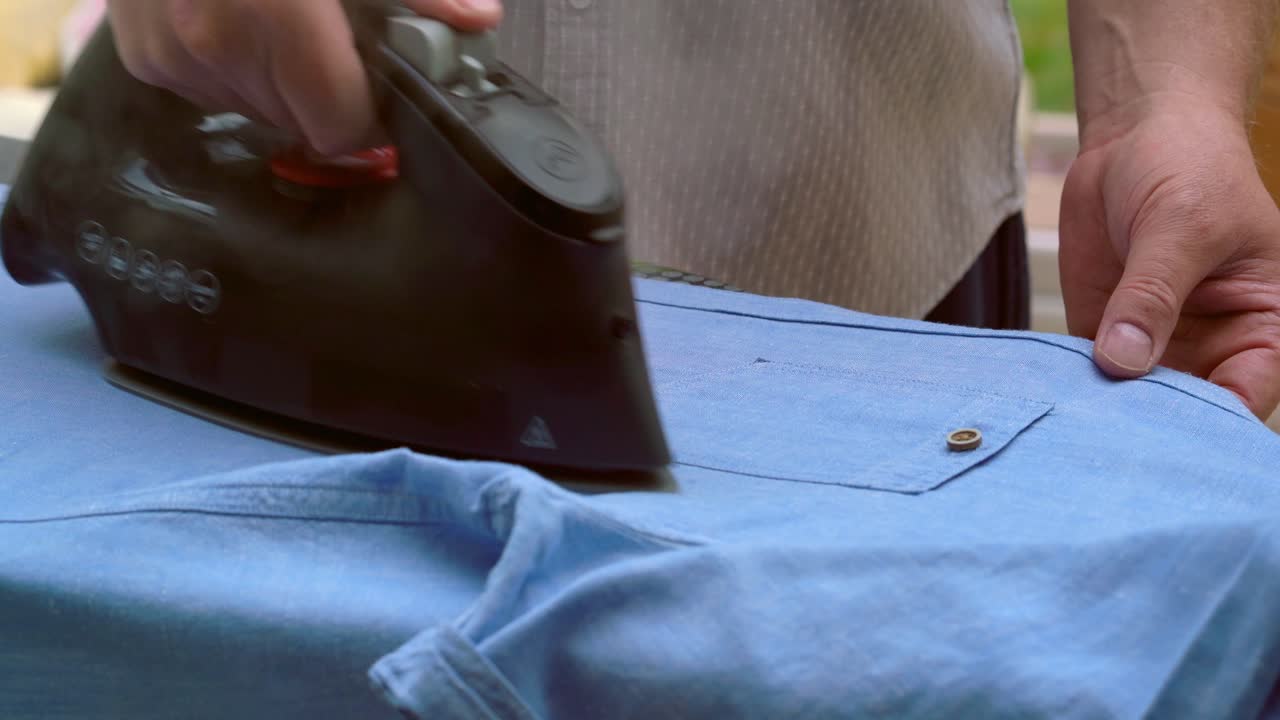 Man Ironing his blue shirt for work steamy