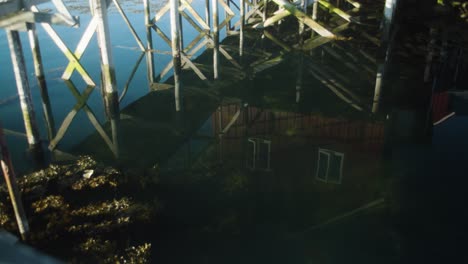 reflections in water of fishing cabin and walkway over ocean, mid shot
