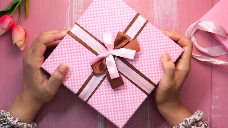 Scatola regalo rosa tra le mani