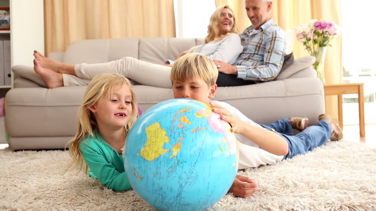 Happy siblings looking at globe on the rug
