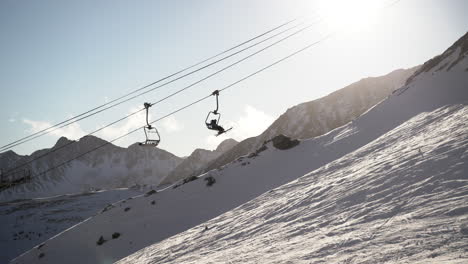 ski lift chairs travelling on cables up snowy mountain moving through bright sunlight