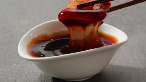 pork in dipping sauce with chopsticks
