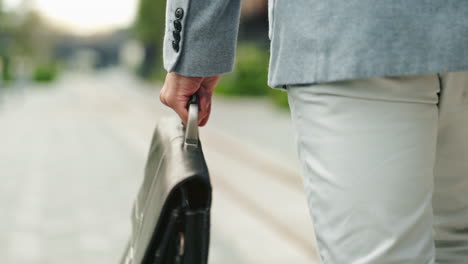 a man in a suit walks down a city street carrying a briefcase