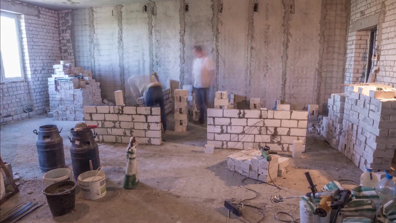 Construtores assentando paredes de tijolos dentro de apartamento com ferramentas profissionais em timelapse. Trabalhadores em ação, pedreiros construindo parede, empreiteiro e operário. Materiais de construção ao redor