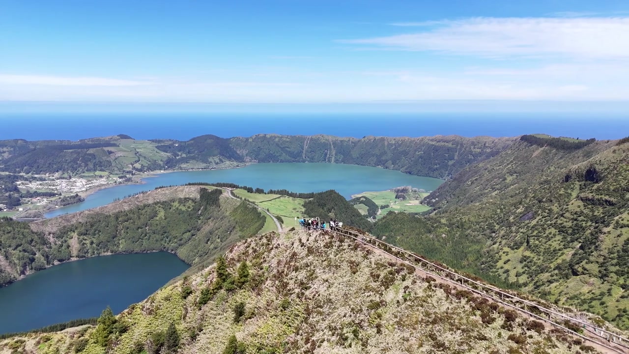 Voo de drone deslumbrante ao longo dos cumes das montanhas com vista para Sete Cidades, na Ilha de São Miguel, Açores. Vista panorâmica das lagoas gémeas, vegetação exuberante e o azul profundo do Oceano Atlântico.