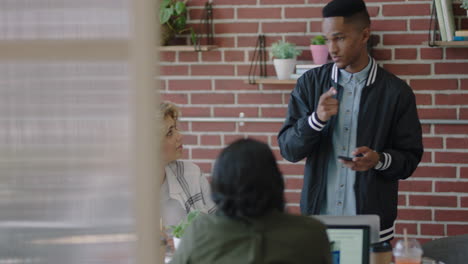 Kreative-Geschäftsleute-Treffen-Sich-Mit-Einem-Afroamerikanischen-Teamleiter,-Der-Die-Strategie-Eines-Startup-Projekts-Bespricht-Und-Entwicklungsideen-Austauscht-Und-Die-Kommunikation-Im-Team-In-Einem-Trendigen-Modernen-Büro-Genießt