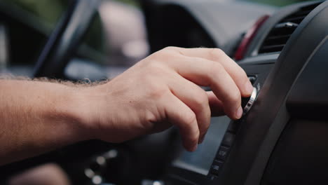 male hand adjusts the tuning of the car radio close-up shot