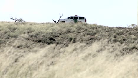 A-car-sits-on-a-hill-with-the-door-open-and-grass-blows-in-the-wind