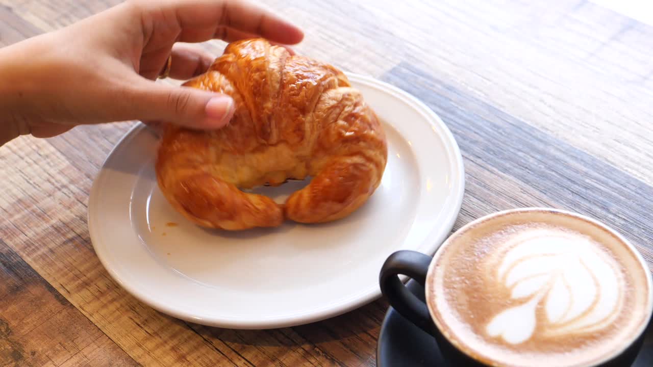 mujer comiendo croissant y latte