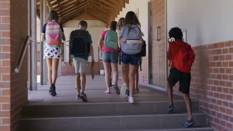 Grupo-De-Niños-Con-Mochilas-Escolares-Caminando-Por-El-Pasillo-De-La-Escuela