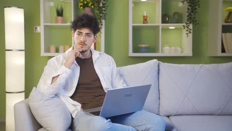 Thoughtful-young-man-using-laptop-at-home.