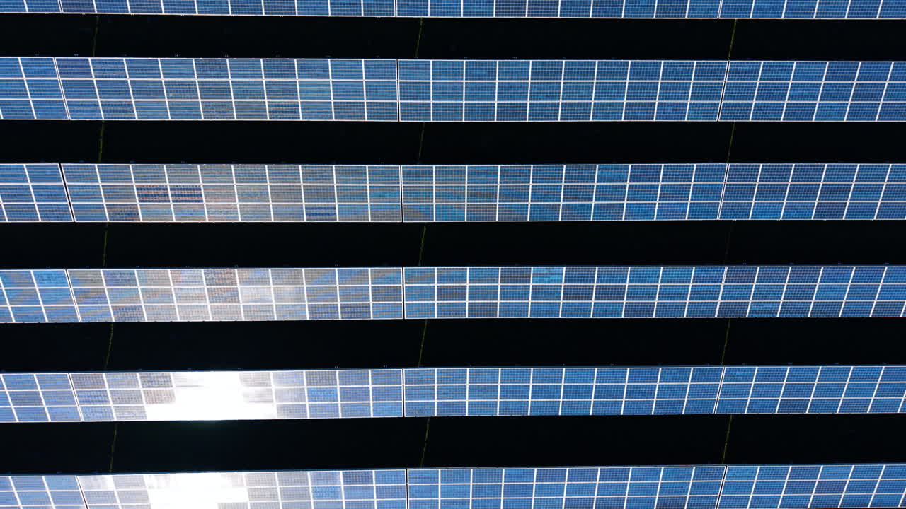 Vista superior de cerca de superficies de paneles fotovoltaicos. Toma técnica aérea que muestra la textura y las filas de paneles solares con sombras oscuras.