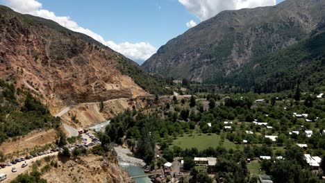 vista aérea hacia atrás del río maule en la zona central con montañas áridas en chile en un día soleado con un pequeño pueblo lleno de vegetación